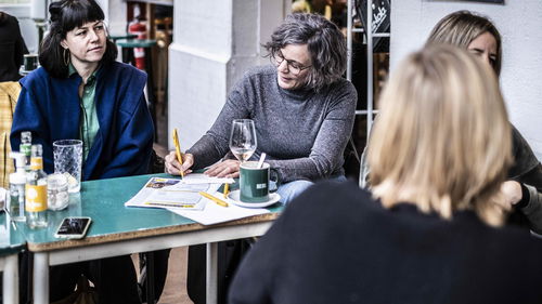 4 vrouwen schrijven samen brieven aan een tafel op cafe